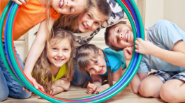 Fünf fröhliche Kinder schauen durch Hula Hoop Reifen