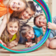 Fünf fröhliche Kinder schauen durch Hula Hoop Reifen